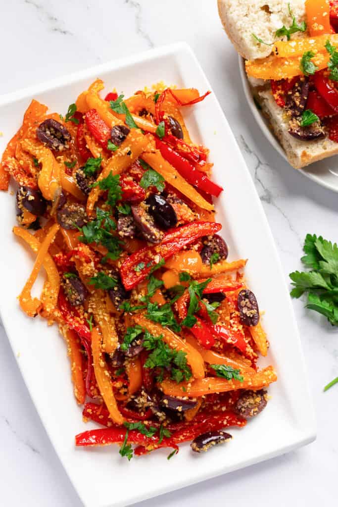 A white platter with tri-colored roasted peppers, Kalamata olives, and Panko breadcrumbs.