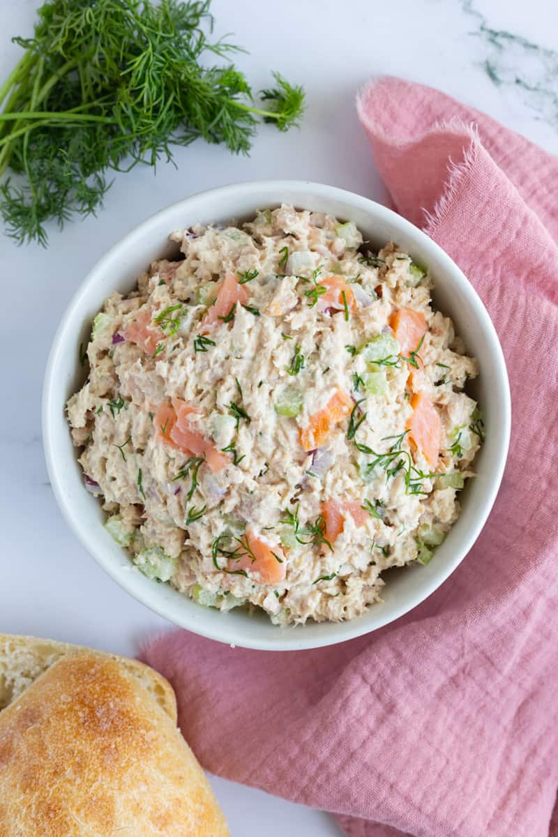 A bowl of tuna salad with chopped smoked salmon, celery, red onion, and fresh dill.