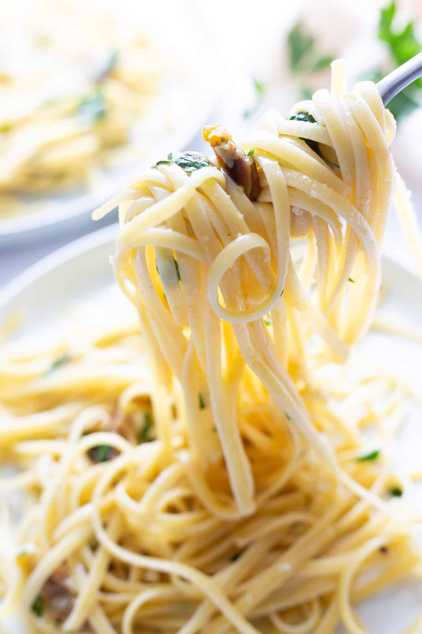 A twirl of linguine with roasted garlic on a fork.