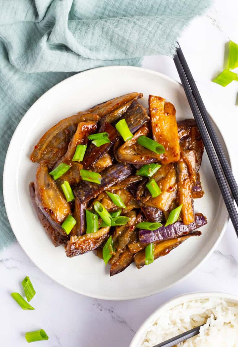 Plate of Chinese eggplant in garlic sauce with a set of chopsticks on the side.