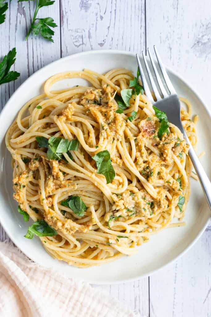 A plate of artichoke and sun-dried tomato pasta garnished with fresh basil.