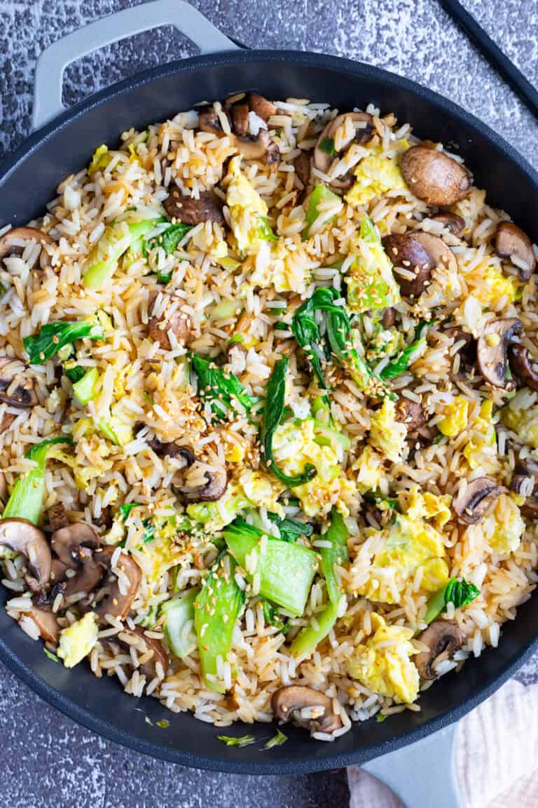 A large skillet filled with fried rice made with bok choy, mushrooms, and eggs.