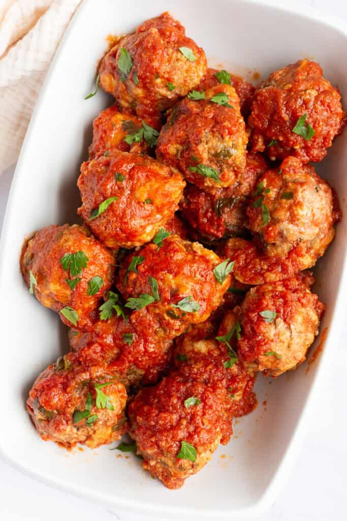 A white platter filled with classic Italian meatballs in red sauce.