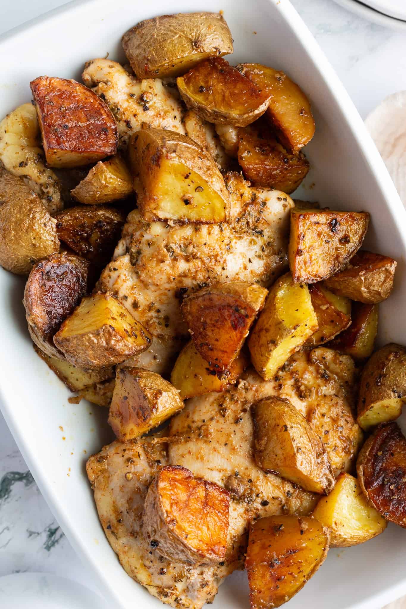 A platter of golden potatoes and chicken thighs.