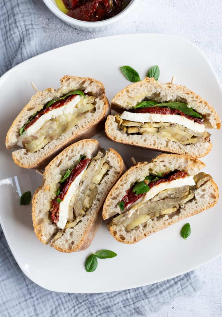 A plate of four eggplant and mozzarella sandwiches.