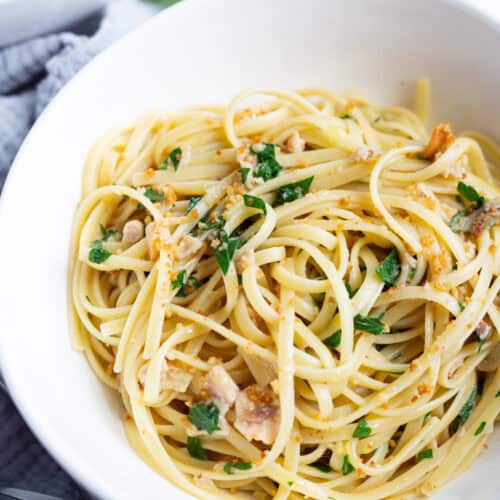 A bowl of linguine with clams, anchovies, and breadcrumbs, garnished with fresh parsley.