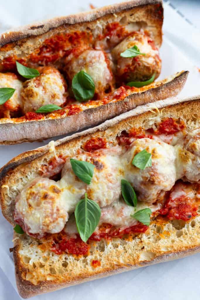 Two meatball Parm heros covered in melted mozzarella and marinara sauce.