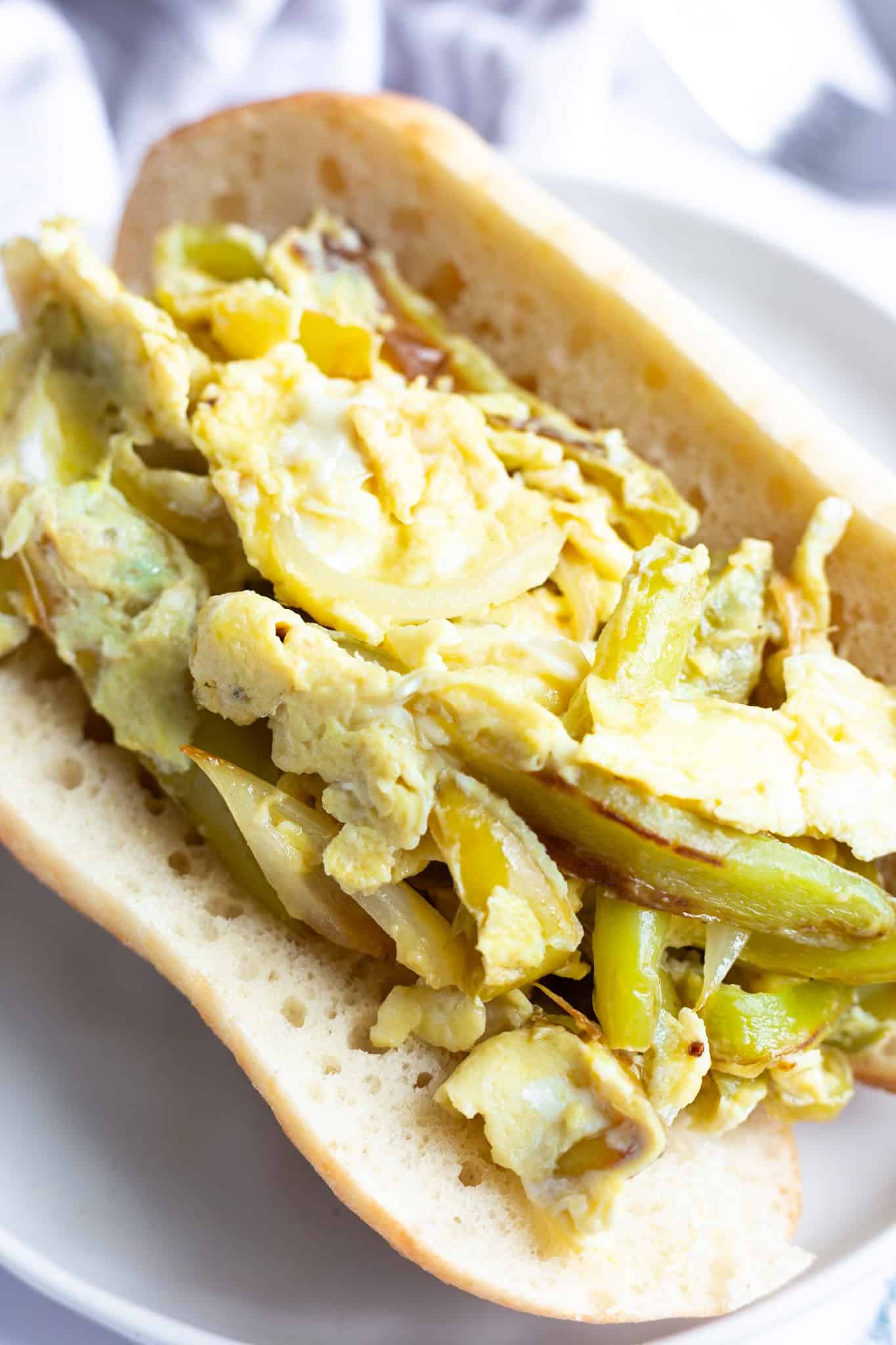 An open hoagie roll filled with peppers and eggs, using cubanelle peppers.