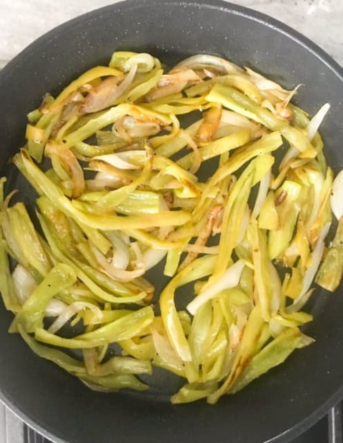 Fully cooked peppers and onions in pan.