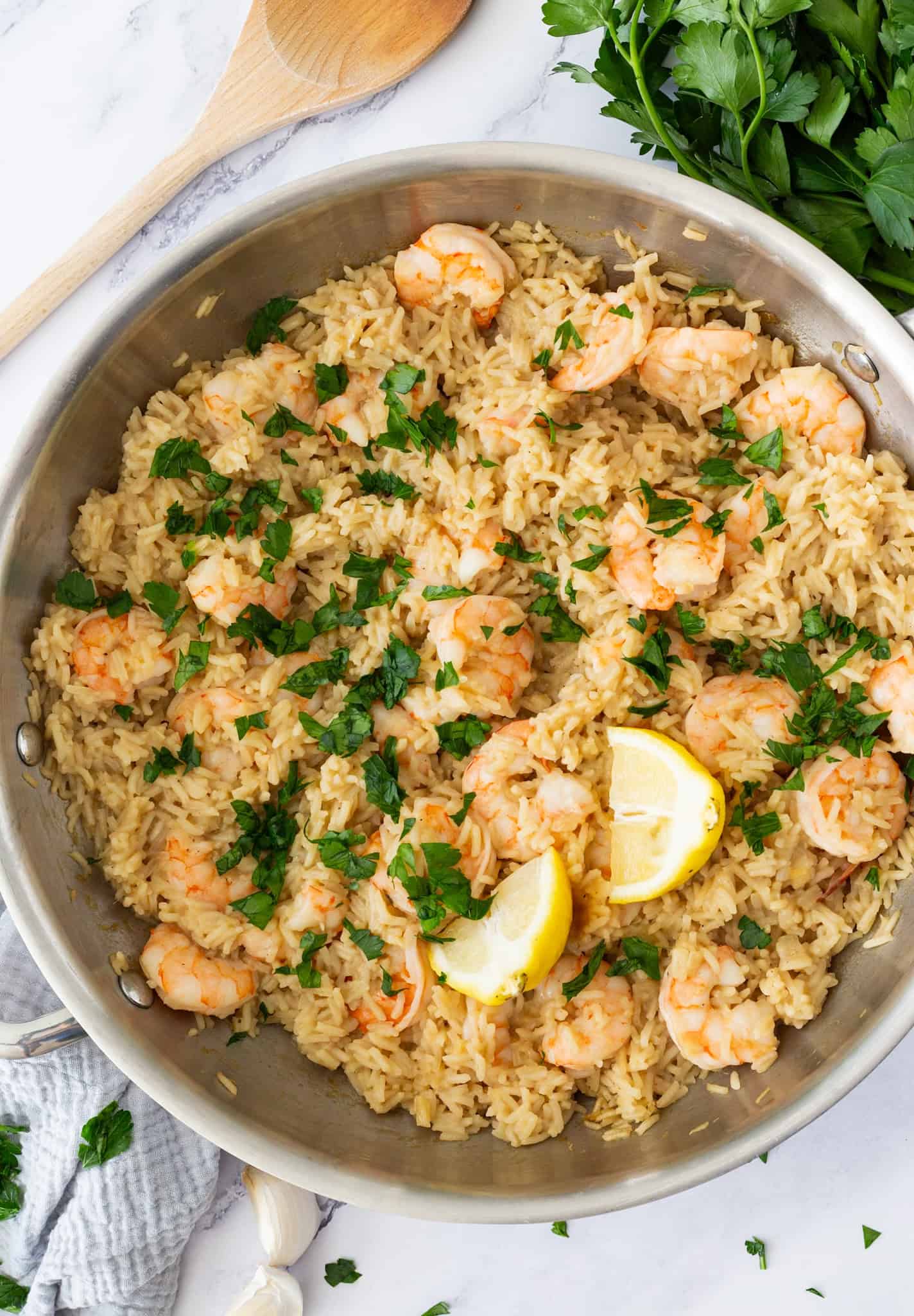 A pan of shrimp and garlic-shallot rice, filled with fluffy rice, juicy shrimp, and a couple of lemon wedges.