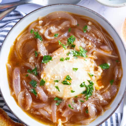 A bowl of Tuscan onion soup with poached egg, garnished with minced parsley.