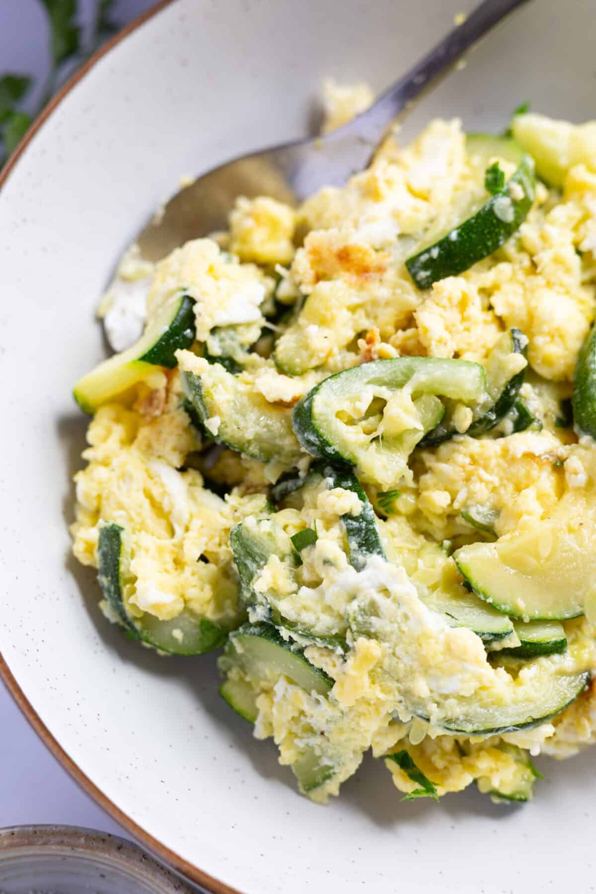 A bowl of scrambled eggs and zucchini.