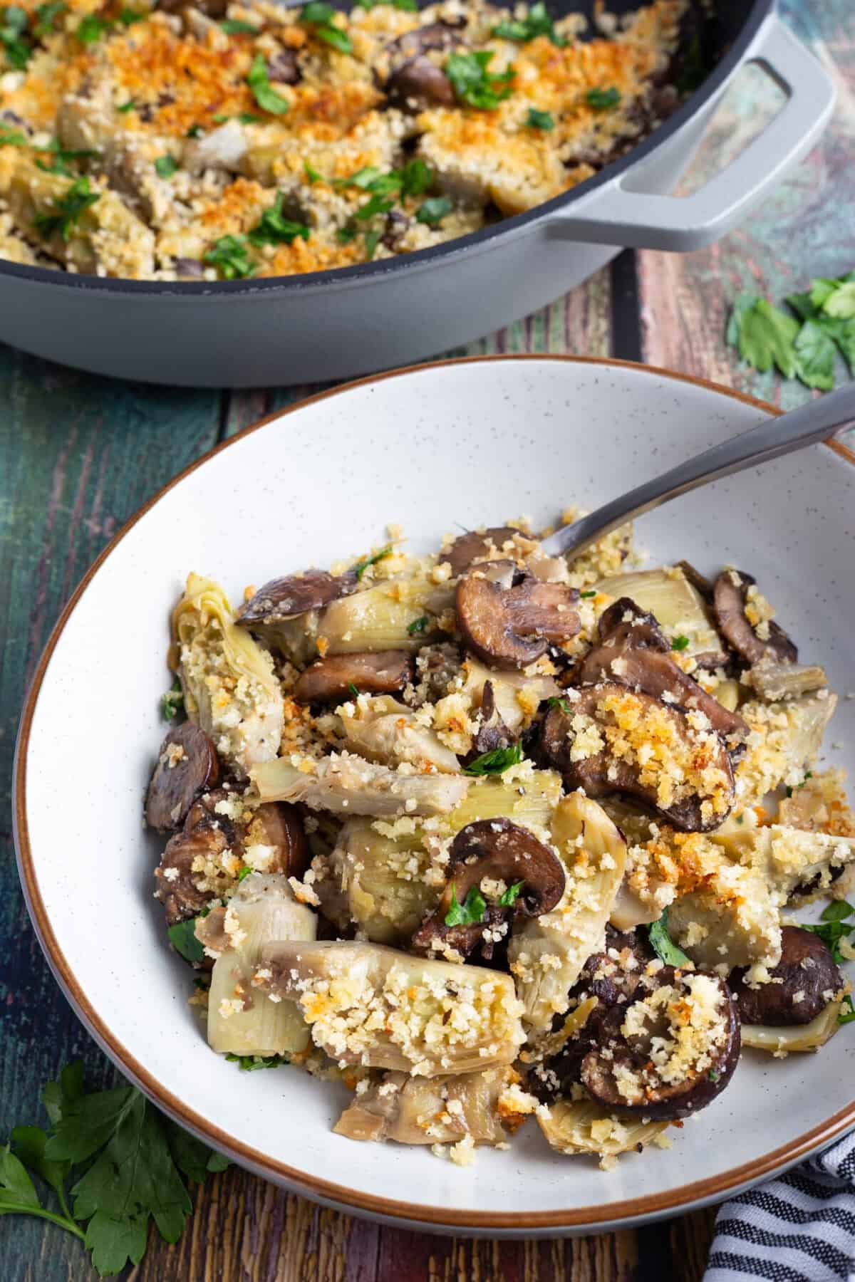 A bowl of sauteed artichoke hearts and mushrooms.
