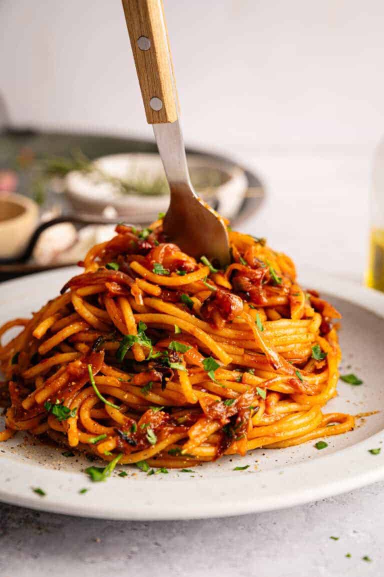 A plate of caramelized shallot pasta held together by a fork.